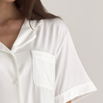 Muse Short PJs — Morning Mist: Close-up of a woman's white short-sleeve pajama top with notched collar and pocket