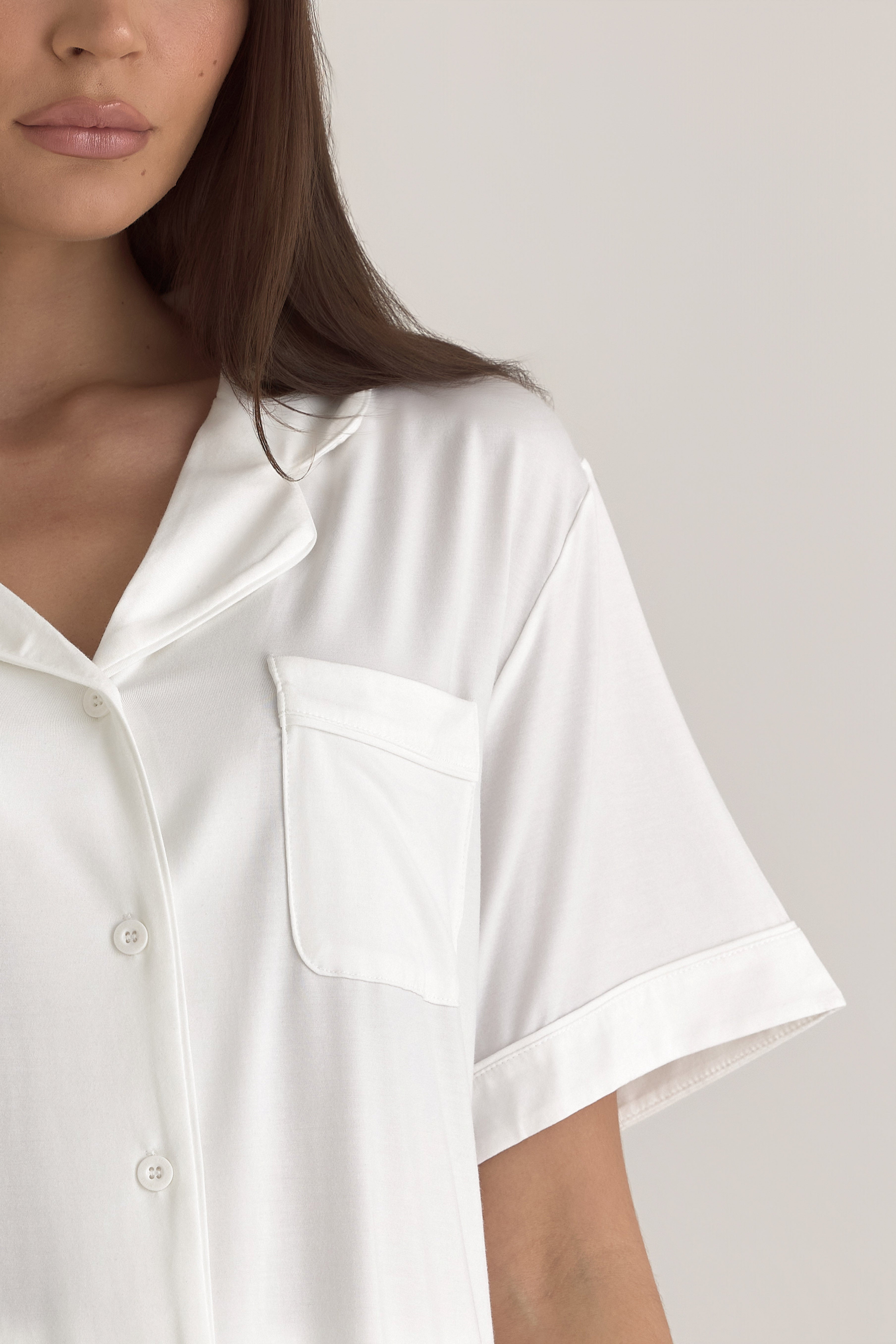 Muse Short PJs — Morning Mist: Close-up of a woman's white short-sleeve pajama top with notched collar and pocket