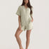 Muse Short PJs in Soft Sage: A woman models a comfortable sage green pajama set with short sleeves and shorts, featuring white piping detail.